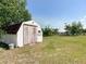 The backyard shed features white siding with a red roof, on a grassy lawn at 258 Nw 122Nd Ave, Oxford, FL 34484