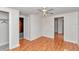 A bedroom with tan-colored hardwood floors, a ceiling fan, and doors to another room, and an accessible closet at 426 Sw 13Th St, Ocala, FL 34471