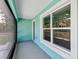 A screen enclosed porch with grey flooring, light blue walls and a large window with a view at 4314 Se 131St Ln, Belleview, FL 34420