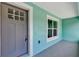 A close up of the front door and window of a light blue house, showcasing the entryway and front porch at 4314 Se 131St Ln, Belleview, FL 34420
