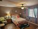 Relaxing main bedroom with a ceiling fan, comfortable furnishings, and a view of the outside through the window at 5024 Se 107Th Pl, Belleview, FL 34420