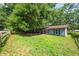 Exterior view of a light-blue single-story home with a lush lawn and framed by mature trees and a wooden fence at 5737 Nw 65Th Pl, Ocala, FL 34482