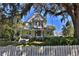 Charming yellow two-story home with a welcoming front porch and white picket fence at 743 E Fort King St, Ocala, FL 34471