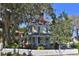Charming two-story home with a porch, landscaped yard, white picket fence and mature trees at 743 E Fort King St, Ocala, FL 34471
