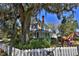 Charming yellow two-story home with a welcoming front porch shaded by beautiful trees at 743 E Fort King St, Ocala, FL 34471