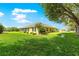 Expansive backyard featuring a well-maintained lawn, mature trees, and a view of the home's screened patio at 13885 Del Webb Blvd, Summerfield, FL 34491