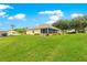 Lush backyard featuring a well-manicured lawn, a screened patio, and mature trees offering privacy and shade at 13885 Del Webb Blvd, Summerfield, FL 34491