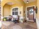 Inviting front porch with rocking chairs, stone pillars, a decorative front door and patterned concrete at 13885 Del Webb Blvd, Summerfield, FL 34491