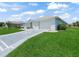 Exterior view of the home showcasing a well-manicured lawn, spacious driveway and attached garage at 17755 Se 117Th Cir, Summerfield, FL 34491