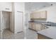 Kitchen with light cabinets, sink, dishwasher, and a view of the laundry room at 17755 Se 117Th Cir, Summerfield, FL 34491