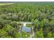 An aerial view of a home surrounded by lush green trees in a serene, wooded setting at 23163 Nw Shamrock Ave, Dunnellon, FL 34431