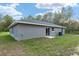 A single-story home with a well-maintained lawn and gray exterior with a sliding glass door at 23163 Nw Shamrock Ave, Dunnellon, FL 34431