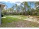 A serene backyard featuring a mix of grass and sandy areas bordered by tall trees, and natural scenery at 23163 Nw Shamrock Ave, Dunnellon, FL 34431
