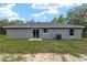 View of backyard, with a sliding door and windows on a gray house with green grass and sand at 23163 Nw Shamrock Ave, Dunnellon, FL 34431