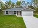 Charming single-story home features a well-manicured lawn, gray exterior, and attached garage for a welcoming curb appeal at 23163 Nw Shamrock Ave, Dunnellon, FL 34431