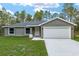 A charming single-story home featuring a well-maintained lawn, gray exterior, and attached garage at 23163 Nw Shamrock Ave, Dunnellon, FL 34431