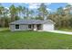 A charming single-story home featuring a well-maintained lawn, gray exterior, and attached garage at 23163 Nw Shamrock Ave, Dunnellon, FL 34431