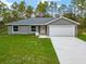 Exterior showcasing a spacious lawn, attached garage, and neutral color scheme at 23163 Nw Shamrock Ave, Dunnellon, FL 34431