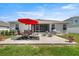 Grassy backyard showcasing a patio with an outdoor dining set, red umbrella, and grill at 5862 Sw 80Th Ln, Ocala, FL 34476