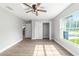 Airy bedroom featuring wood-look floors, a modern ceiling fan, closet, and large window with a picturesque view at 7483 Sw 121St Ter, Dunnellon, FL 34432