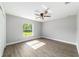 Sunlit bedroom with wood-look floors, contemporary ceiling fan, and a large window offering a peaceful outdoor view at 7483 Sw 121St Ter, Dunnellon, FL 34432