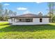 Home exterior showcasing a covered patio, white stucco and lush green lawn at 7483 Sw 121St Ter, Dunnellon, FL 34432