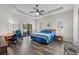Bright main bedroom features tray ceilings, wood-look floors, a ceiling fan, desk area and sliding glass doors to the patio at 808 Overlook Grove Dr, Winter Haven, FL 33884