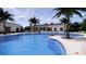 Resort-style pool and community club house featuring palm trees, lounge chairs, and clear blue water for relaxation at 8578 Pinecrest Trl, Wildwood, FL 34785
