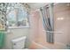 Bathroom with a bathtub and shower, light pink tile, and a window with decorative curtain at 10347 Se 178Th Pl, Summerfield, FL 34491