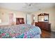 Well-lit bedroom with hardwood floors featuring floral bedding, a ceiling fan, and natural light creating a warm and cozy space at 10347 Se 178Th Pl, Summerfield, FL 34491