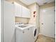 Laundry room featuring white washer and dryer, storage cabinets, and a utility door at 10347 Se 178Th Pl, Summerfield, FL 34491