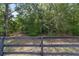 A wooden fence marks the property line, offering privacy and security against a backdrop of lush greenery at 11447 Sw 128Th Ave, Dunnellon, FL 34432