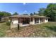 Back of the house with a covered patio and enclosed sunroom surrounded by lush greenery at 11447 Sw 128Th Ave, Dunnellon, FL 34432