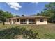 Home's rear exterior with a sunroom, covered patio and large back yard at 11447 Sw 128Th Ave, Dunnellon, FL 34432