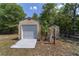 View of shed featuring roll up door and ramp alongside surrounding greenery and fencing at 11447 Sw 128Th Ave, Dunnellon, FL 34432