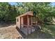 Quaint shed with a covered porch and traditional door, surrounded by trees and set against a neat grassy yard at 11447 Sw 128Th Ave, Dunnellon, FL 34432