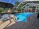 Screened-in in-ground pool features a ladder for easy access, pavers, and lounge chairs at 11651 Sw 77Th Cir, Ocala, FL 34476