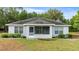 A view of the back exterior of a house with a screened lanai, windows and neutral-colored siding at 15465 Se 113Th Street Rd, Ocklawaha, FL 32179