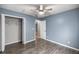 Blue bedroom features wood-look floors, closet, and ceiling fan at 15465 Se 113Th Street Rd, Ocklawaha, FL 32179