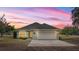 Charming single-story home with a well-maintained lawn and attached two-car garage in a lovely neighborhood at sunset at 15465 Se 113Th Street Rd, Ocklawaha, FL 32179