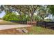 View of the property featuring a driveway, fence, mature trees, and lush green lawn at 15465 Se 113Th Street Rd, Ocklawaha, FL 32179
