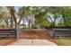 View of the property featuring a driveway, mature trees, green lawn, and metal fencing at 15465 Se 113Th Street Rd, Ocklawaha, FL 32179