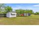 Yard view of the property featuring three small barns, swing set, and grassy surroundings at 15465 Se 113Th Street Rd, Ocklawaha, FL 32179