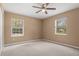 Neutral bedroom featuring plush carpet, natural light from two windows, and a ceiling fan at 1617 Se 29Th Ter, Ocala, FL 34471