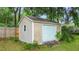 Tan shed with a white garage door and single window nestled in a green yard with trees and partial fence at 1617 Se 29Th Ter, Ocala, FL 34471