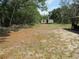 Exterior shot of a single-wide mobile home on a spacious lot with mature trees and partially cleared land at 1737 Griffin Ave, Lady Lake, FL 32159