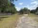 Exterior view of multiple structures including barns and a house on a fenced lot with mature trees at 1737 Griffin Ave, Lady Lake, FL 32159