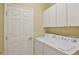 Functional laundry room equipped with a washer, dryer, and ample overhead storage cabinets at 2550 Nw 55Th Avenue Rd, Ocala, FL 34482