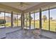 Bright sunroom showcasing golf course views and white wicker furniture to relax and entertain guests at 2550 Nw 55Th Avenue Rd, Ocala, FL 34482