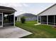 Exterior view of screened in back porches and an expanse of green grass in the backyard at 2594 Berrington Loop, The Villages, FL 32162
